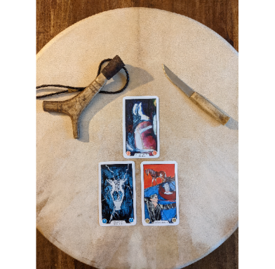 A sacred drum with a Nordic-style antler talisman and ritual knife, featuring a three-card tarot reading laid on top, symbolizing divination