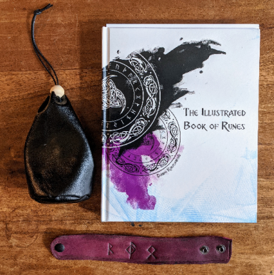 A copy of The Illustrated Book of Runes alongside a black leather rune pouch and a purple rune-engraved bracelet, symbolizing the study and 