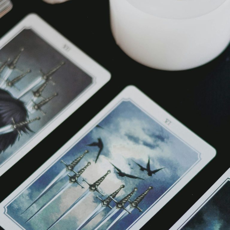 A tarot reading with dark-themed tarot cards, including the Eight of Swords and Death card, alongside a lit white candle, for transformation