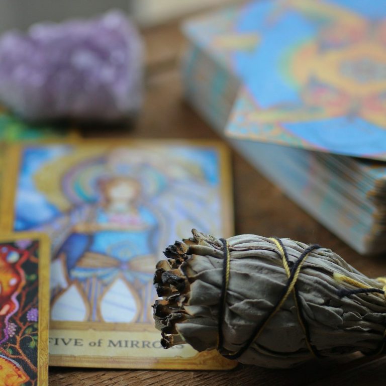 A tarot reading with tarot cards, sage for cleansing energy, and amethyst crystals, symbolizing spiritual practice and divination.